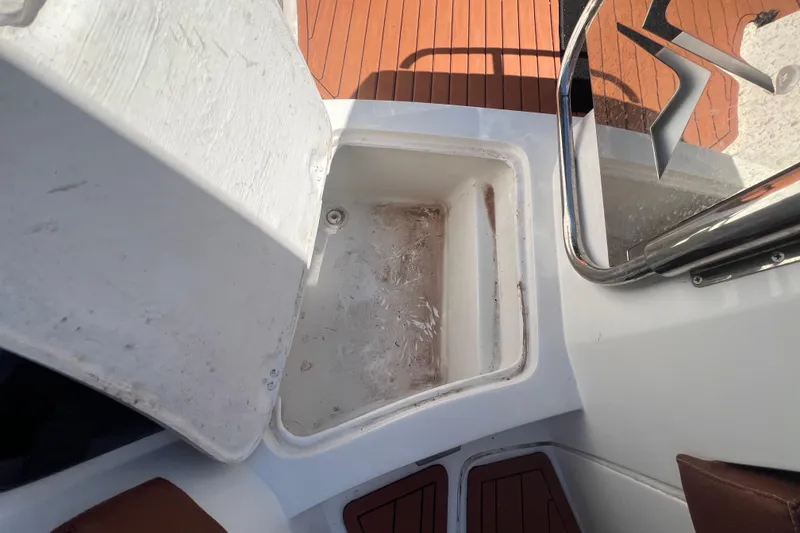 Slide: The Image of Open storage compartment on 2024 NX Boats 290 Exclusive, featuring teak flooring and stainless steel railing. - 53