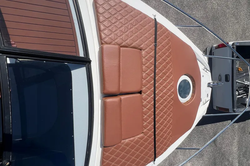 Slide: The Image of 2024 NX Boats 290 Exclusive with brown quilted deck cushions and circular window. - 60