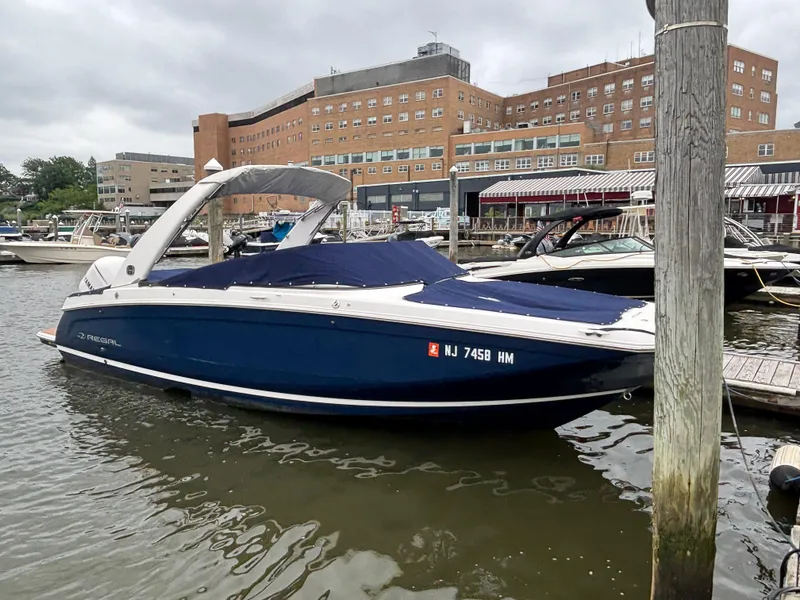 The Image of 2019 Regal 26 OBX boat docked in marina, blue cover, urban backdrop. - 0