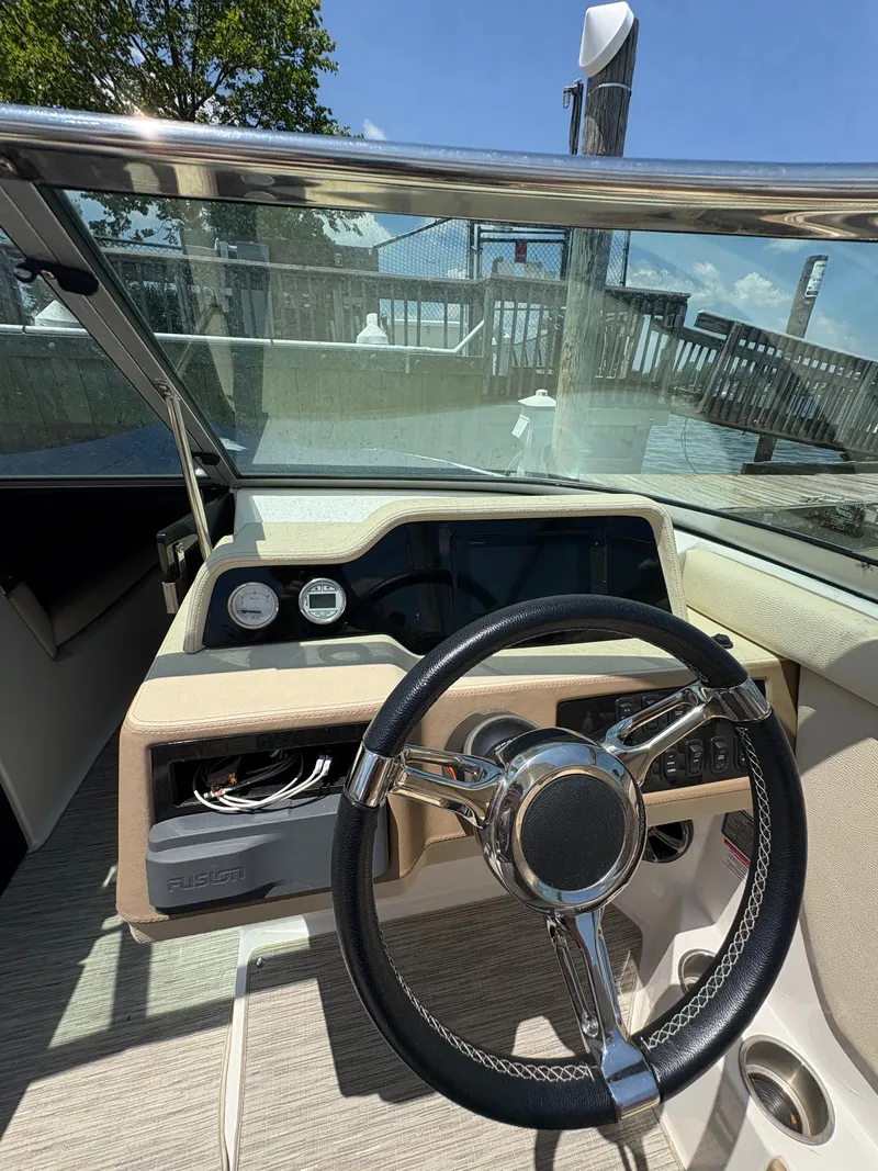 Slide: The Image of 2019 Regal 26 OBX boat dashboard with steering wheel and gauges, docked by the water. - 10