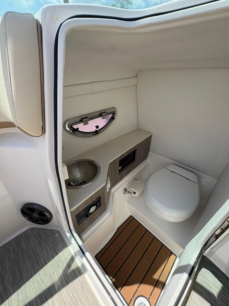 Slide: The Image of 2019 Regal 26 OBX boat interior with compact bathroom, featuring a toilet and sink. - 13