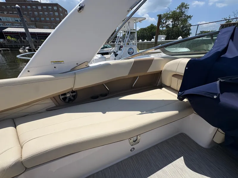 Slide: The Image of 2019 Regal 26 OBX boat interior with beige seating and blue cover, docked by the water. - 3