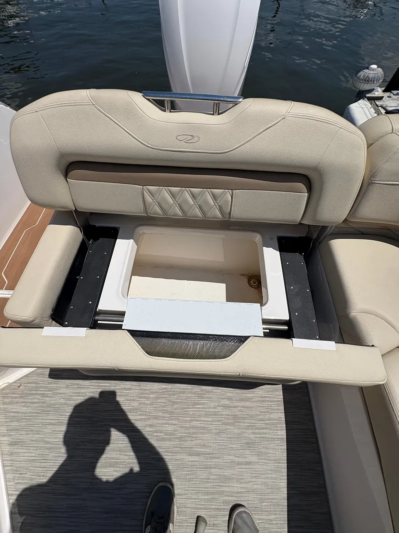 Slide: The Image of 2019 Regal 26 OBX boat seat with storage compartment open, docked by the water. - 9