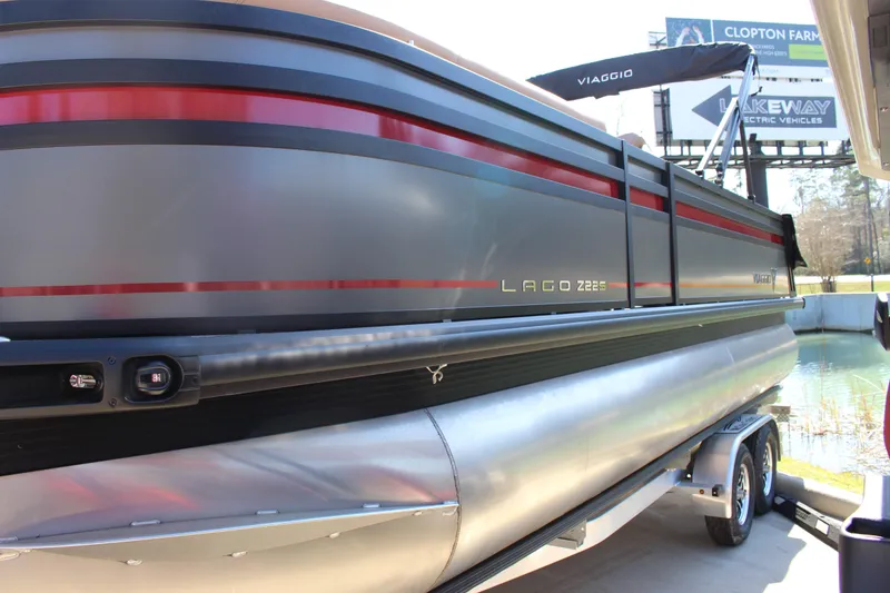 Slide: The Image of 2025 Viaggio Lago Z22S CC pontoon boat on trailer, sleek design with red accents. - 3