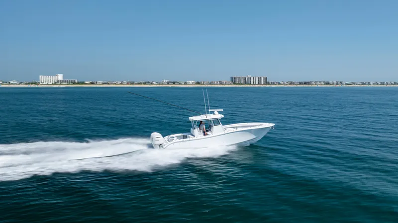 Slide: The Image of 2026 Yellowfin 36 Offshore boat cruising on open water near coastal buildings. - 38