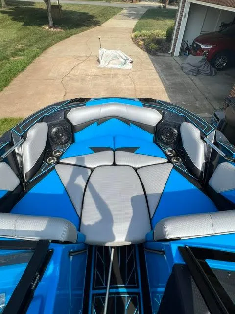 Slide: The Image of 2022 Centurion Fi23 boat interior with blue and gray seating, parked in a driveway. - 7