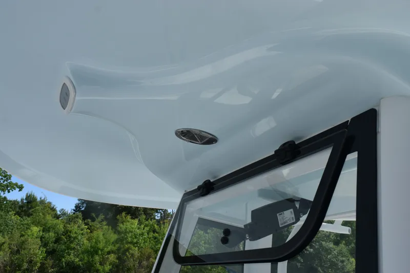 Slide: The Image of 2026 Sea Hunt Ultra 245 SE boat roof and window detail with lush greenery background. - 14