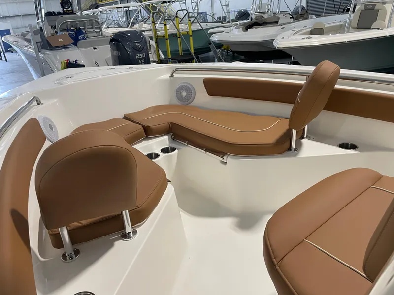 Slide: The Image of 2025 Key West 203 FS boat interior with tan seating and cup holders in a showroom. - 17
