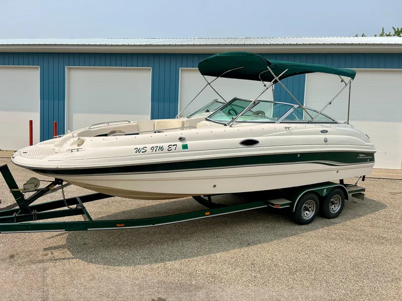 The Image of 2000 Chaparral Sunesta 233 boat on trailer, parked outside blue building. - 0