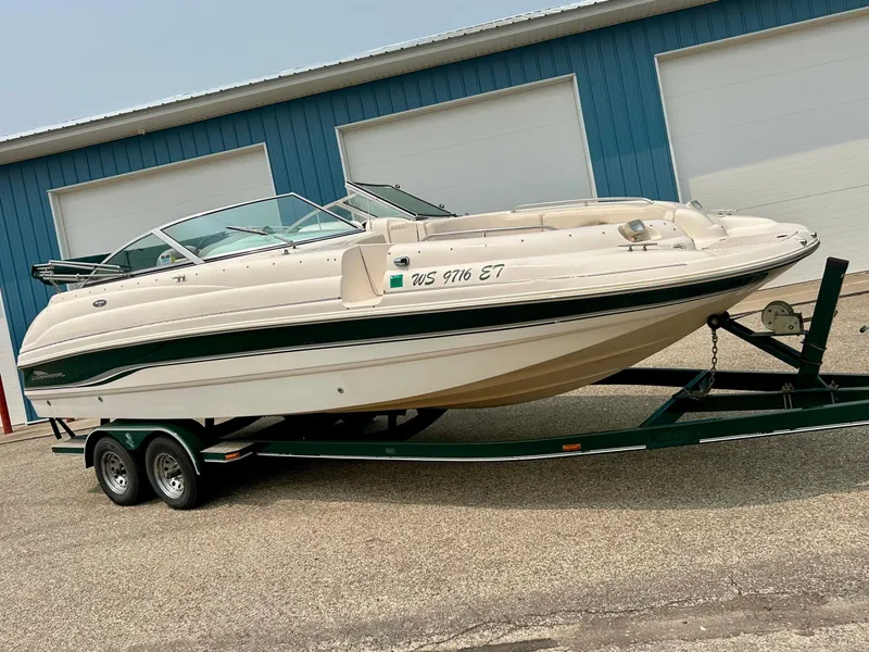 Slide: The Image of 2000 Chaparral Sunesta 233 boat on trailer, parked near blue building. - 2
