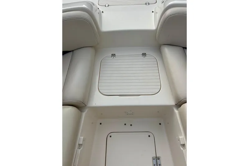 Slide: The Image of 2000 Chaparral Sunesta 233 boat interior with white seating and storage compartments. - 52