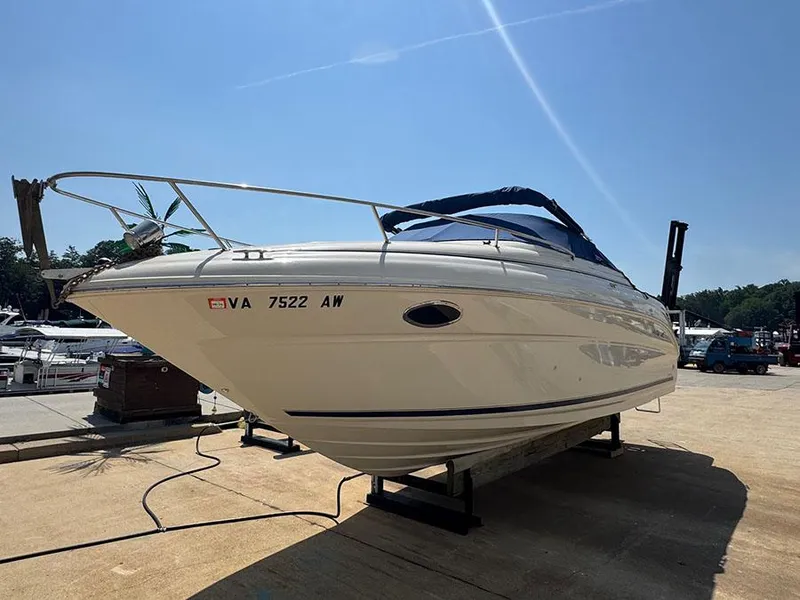 Slide: The Image of 2001 Sea Ray 245 Weekender boat on a stand under clear blue sky. - 3