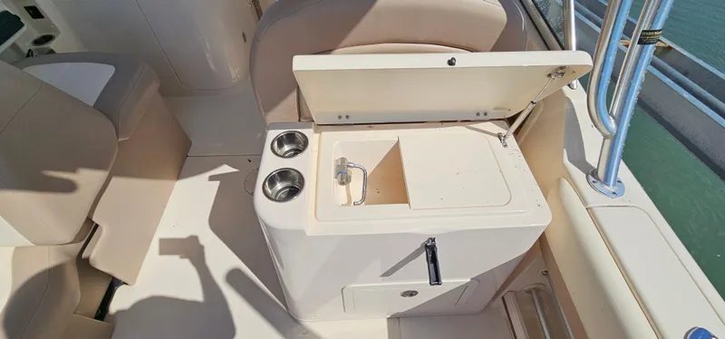 Slide: The Image of 2014 Grady-White Freedom 285 boat interior with helm, seating, and cup holders by the water. - 12