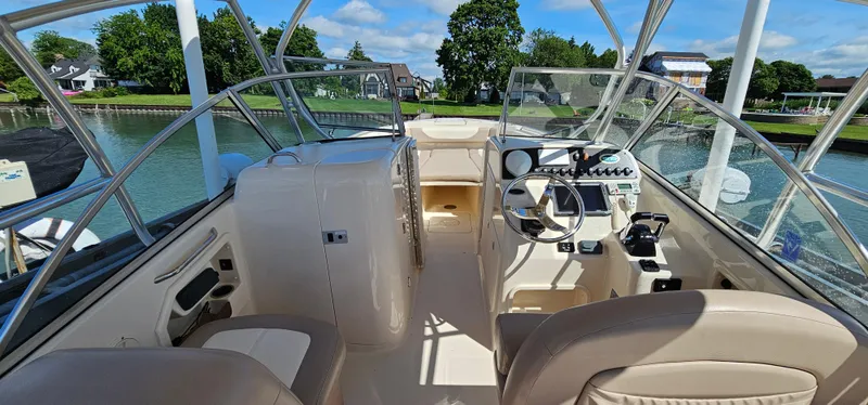 Slide: The Image of 2014 Grady-White Freedom 285 boat interior with steering wheel and seating, docked by a scenic waterfront. - 14