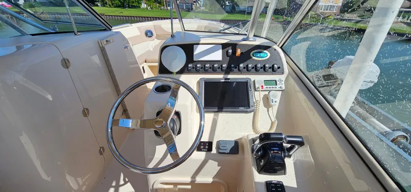 Slide: The Image of 2014 Grady-White Freedom 285 boat interior with steering wheel and controls, docked by a scenic waterfront. - 15