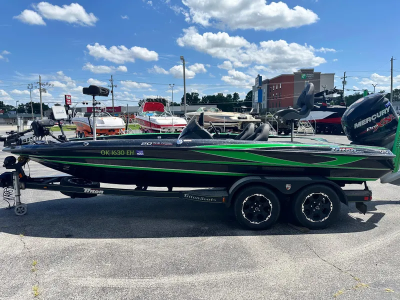 Slide: The Image of 2020 Triton 20 TRX Patriot boat with green accents on a trailer, parked outdoors. - 5