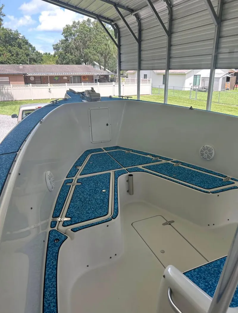 Slide: The Image of 1996 Pro-Line 27 CC boat interior under a metal canopy, featuring blue deck padding. - 8