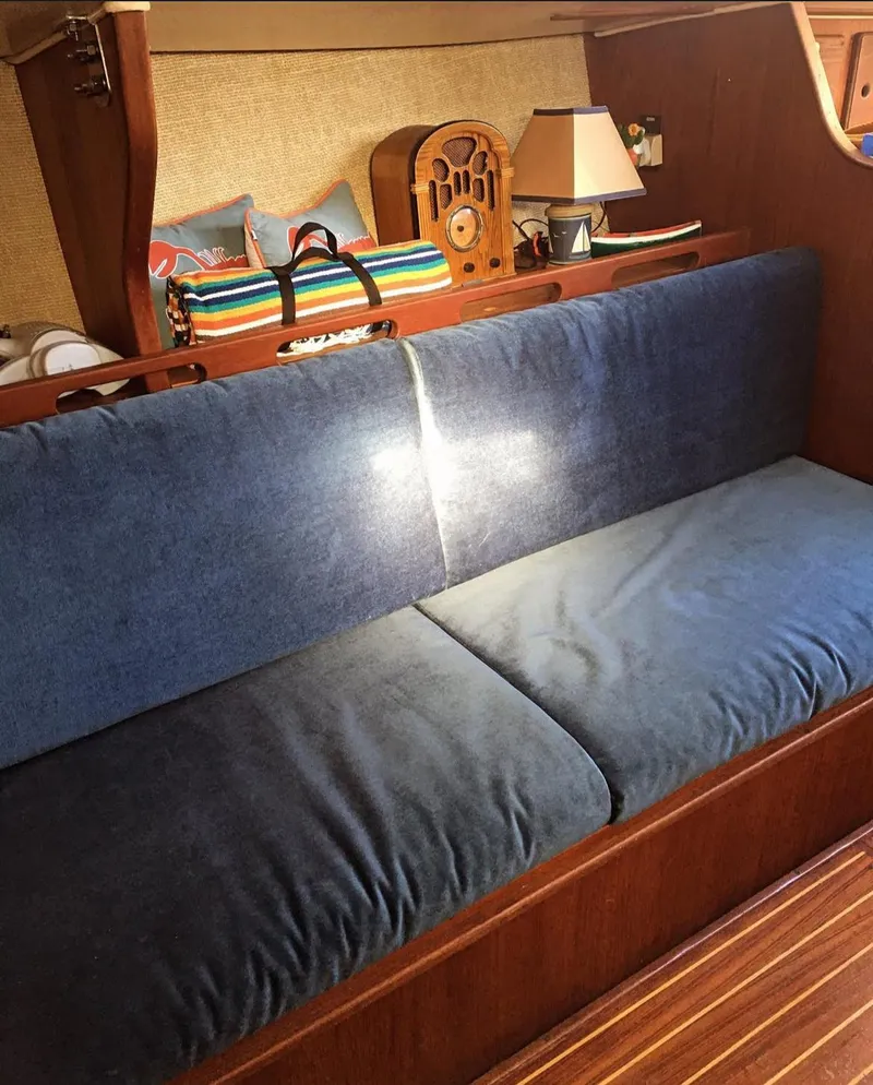 Slide: The Image of Interior of a 1982 Morgan 32 sailboat with blue cushioned seating and wooden accents. - 3