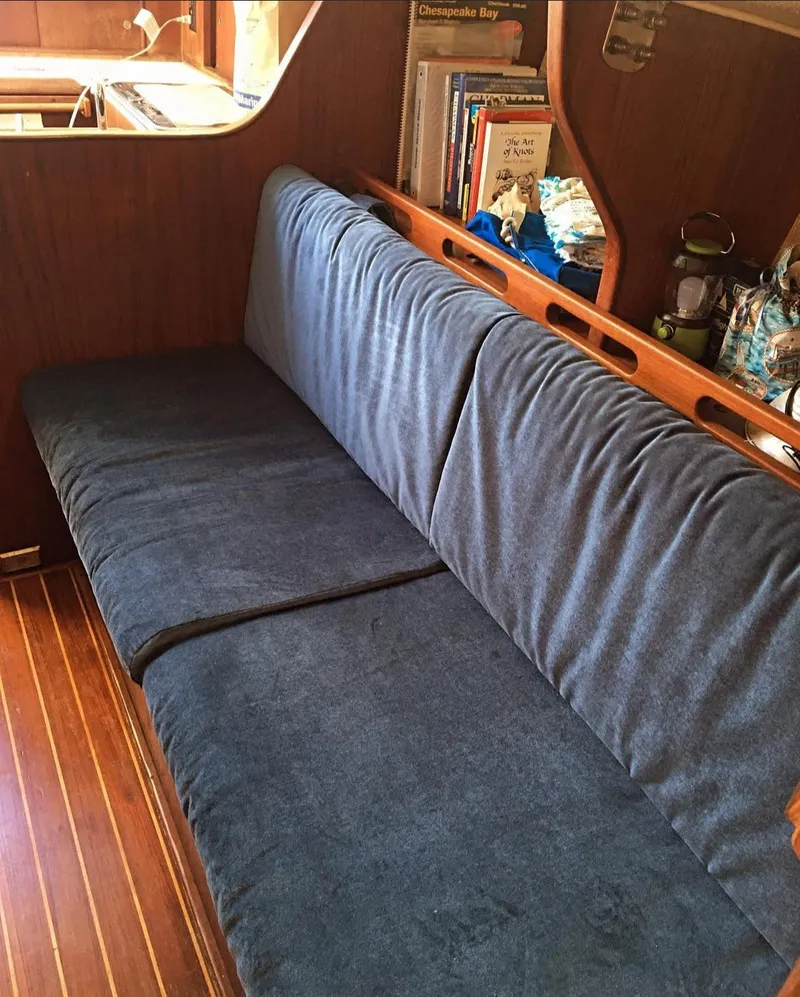 Slide: The Image of 1982 Morgan 32 sailboat interior with blue cushioned seating and wooden accents. - 4