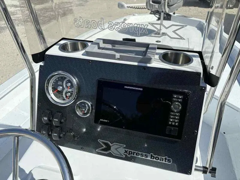 Slide: The Image of 2026 Xpress H22B boat dashboard with gauges, Humminbird display, and cup holders. - 15