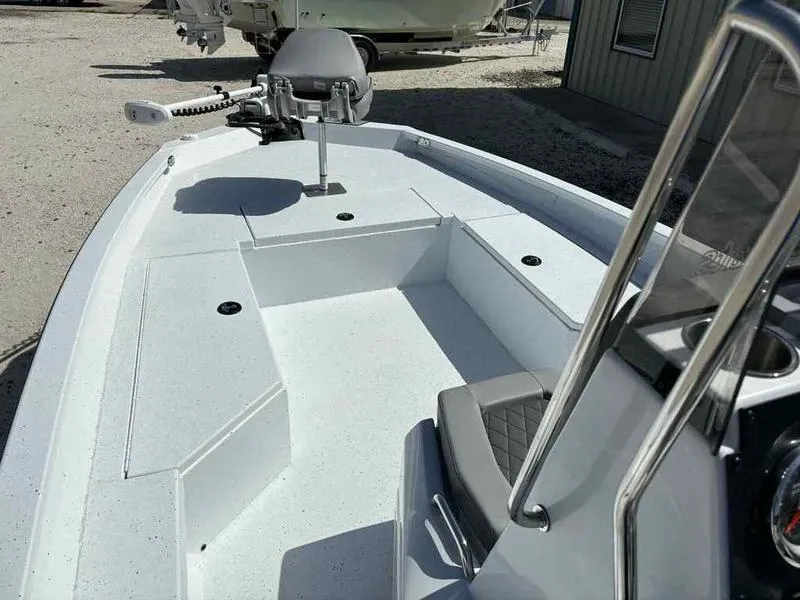 Slide: The Image of 2026 Xpress H22B boat interior with seating and steering console, parked outdoors. - 8