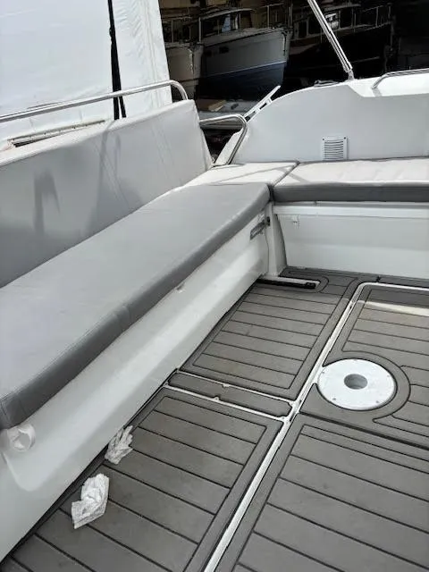 Slide: The Image of 2019 Beneteau Antares 27 boat interior with gray seating and deck flooring. - 11