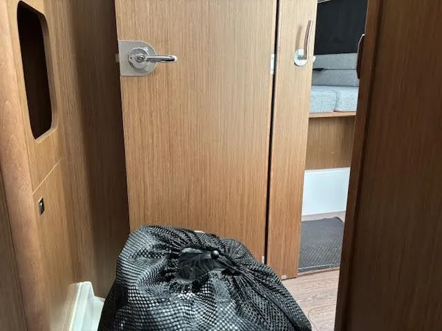 Slide: The Image of Interior of 2019 Beneteau Antares 27 with wooden door and black mesh bag. - 32