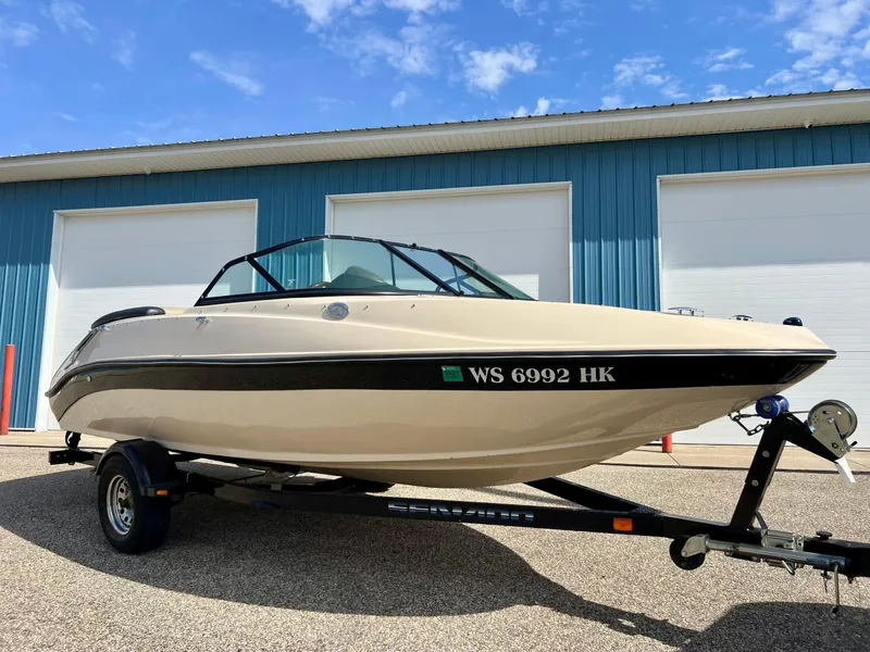 The Image of 2007 Sea-Doo 205 Utopia boat on trailer, parked outside blue building under clear sky. - 0