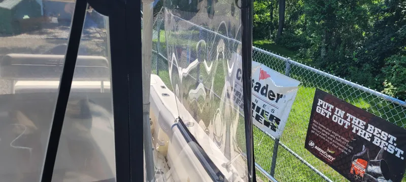 Slide: The Image of Boston Whaler 240 Outrage boat, side view, near fence with advertising banners. - 11