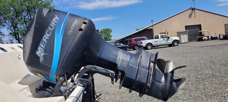 Slide: The Image of Mercury Optimax outboard motor on a 2000 Boston Whaler 240 Outrage, parked near a warehouse. - 12