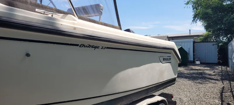 Slide: The Image of Boston Whaler 240 Outrage 2000 boat on trailer, parked outdoors. - 2