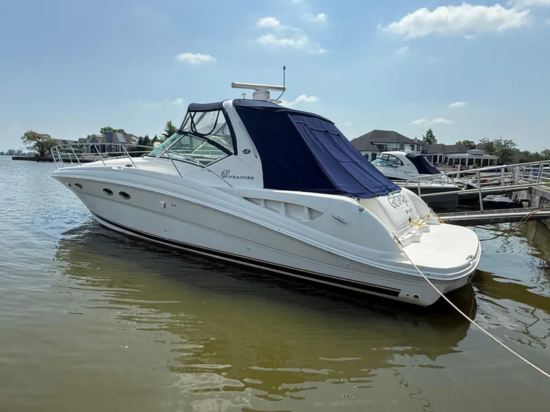 The Image of 2003 Sea Ray 420 Sundancer yacht docked in a marina under a clear blue sky. - 1