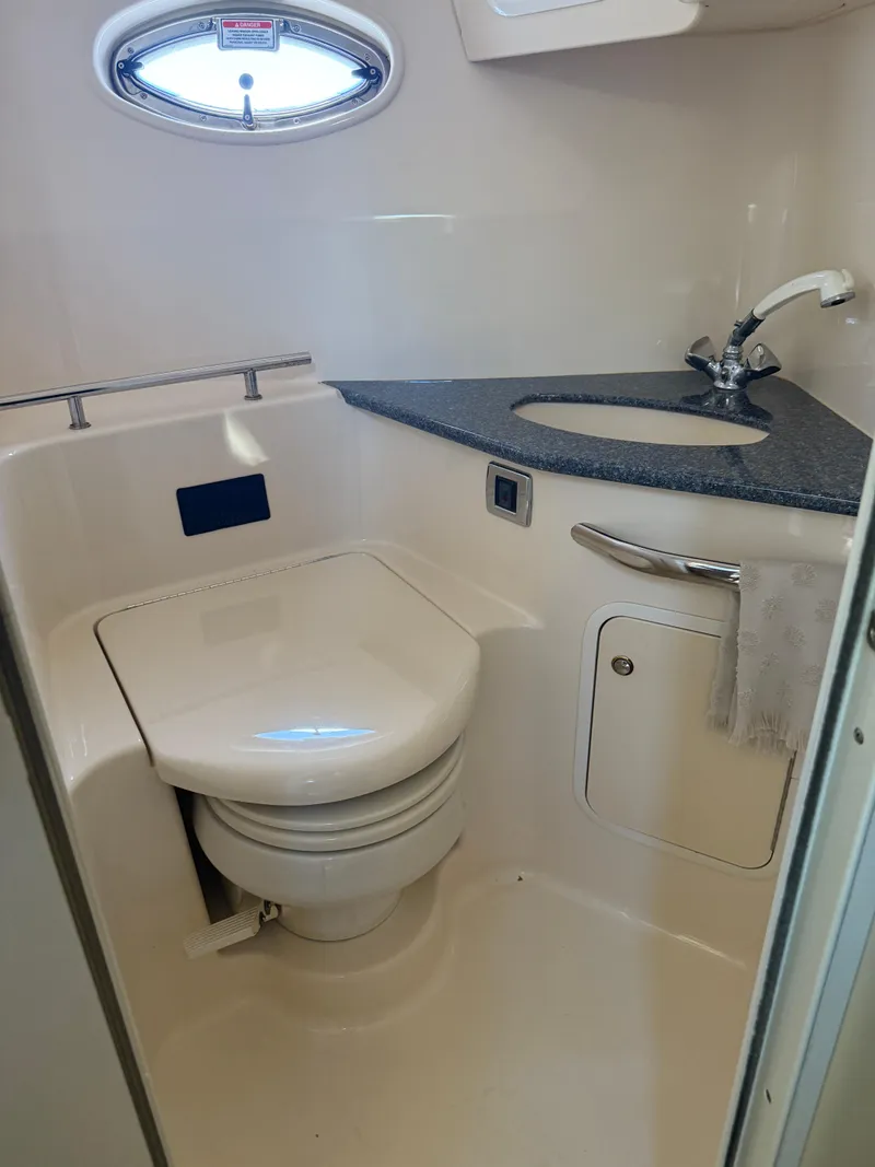 Slide: The Image of 2003 Sea Ray 420 Sundancer bathroom with toilet, sink, and porthole window. - 8