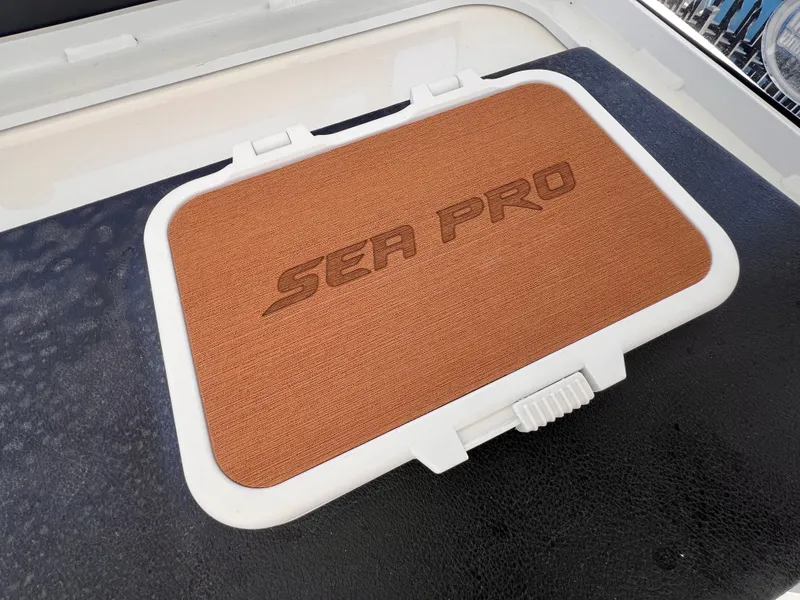 Slide: The Image of Sea Pro 262 Sport 2026 boat compartment with logo on brown cover. - 24