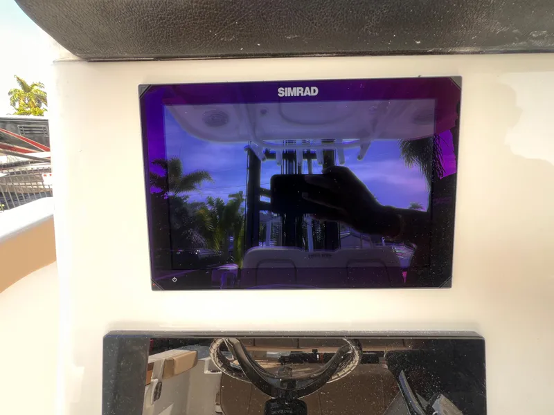 Slide: The Image of Simrad display on 2026 Sea Pro 262 Sport boat dashboard, reflecting palm trees. - 26