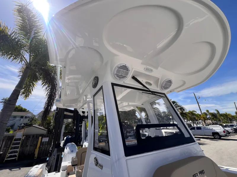 Slide: The Image of 2026 Sea Pro 262 Sport boat with T-top and speakers, parked under palm trees. - 28