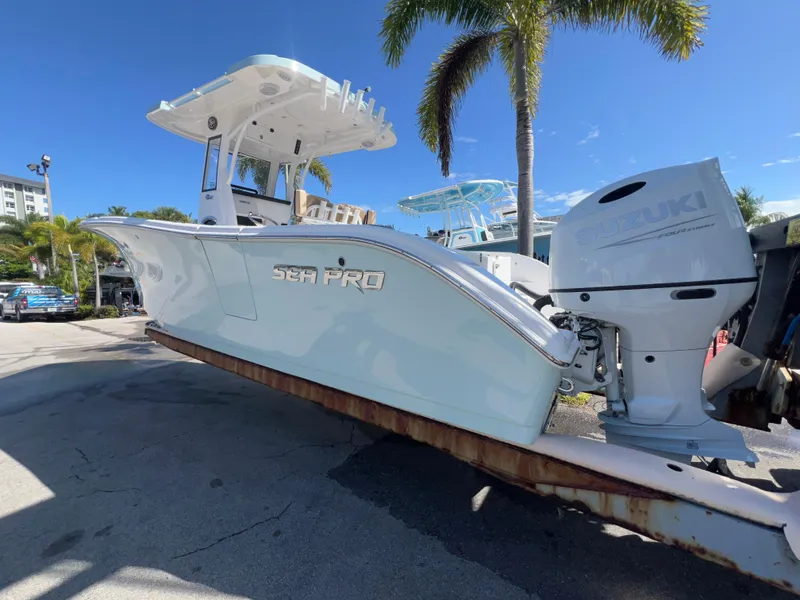 Slide: The Image of 2026 Sea Pro 262 Sport boat with Suzuki engine, parked under palm trees. - 3