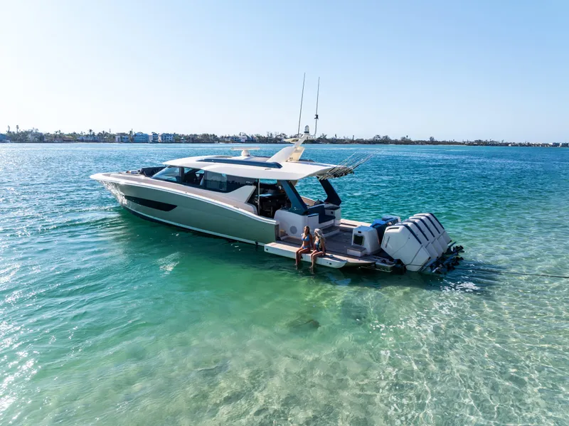 Slide: The Image of 2026 Scout 670 LXS yacht anchored in clear turquoise water, with people relaxing on the deck. - 6