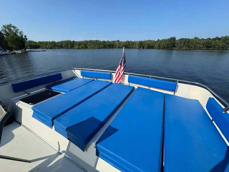 Slide: The Image of 1985 Bluewater Yachts 51 Coastal Cockpit MY with blue seating, American flag, on a serene lake. - 10