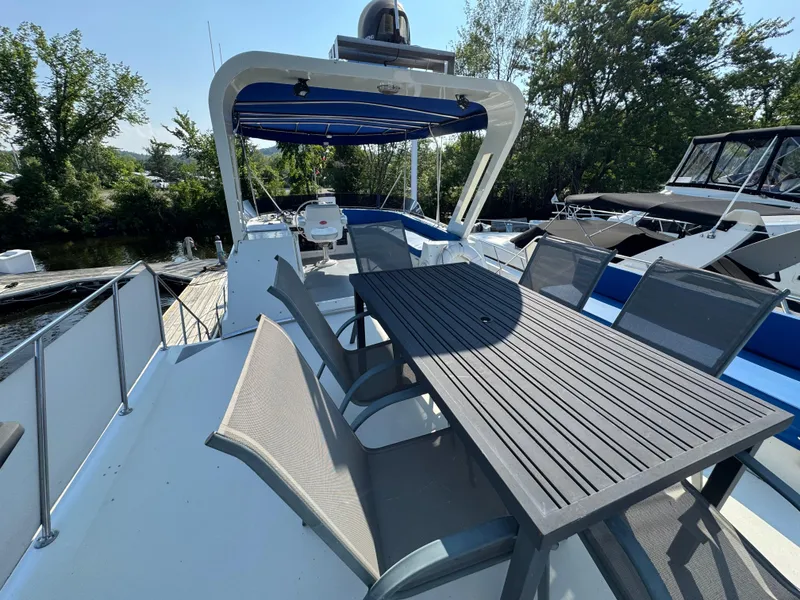 Slide: The Image of 1985 Bluewater Yachts 51 Coastal Cockpit MY with outdoor seating and canopy, docked by trees. - 11