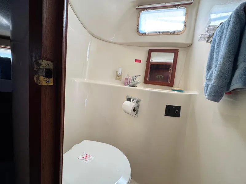 Slide: The Image of 1985 Bluewater Yachts 51 Coastal Cockpit MY bathroom with toilet, sink, and mirror. - 36