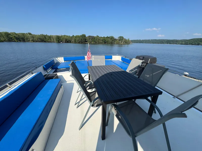 Slide: The Image of 1985 Bluewater Yachts 51 Coastal Cockpit MY with outdoor seating and table on a serene lake. - 9