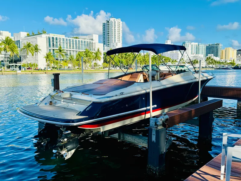 The Image of 2015 Chris-Craft Launch 32 boat docked in a sunny marina with cityscape background. - 0