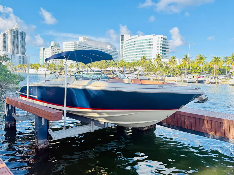 Slide: The Image of 2015 Chris-Craft Launch 32 boat docked in a sunny marina with cityscape background. - 2
