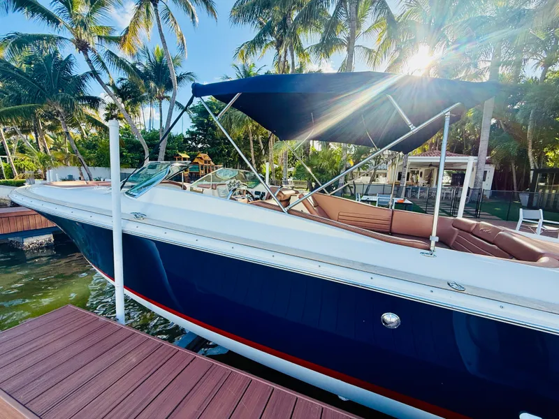Slide: The Image of 2015 Chris-Craft Launch 32 boat docked under palm trees, with sun shining through canopy. - 6