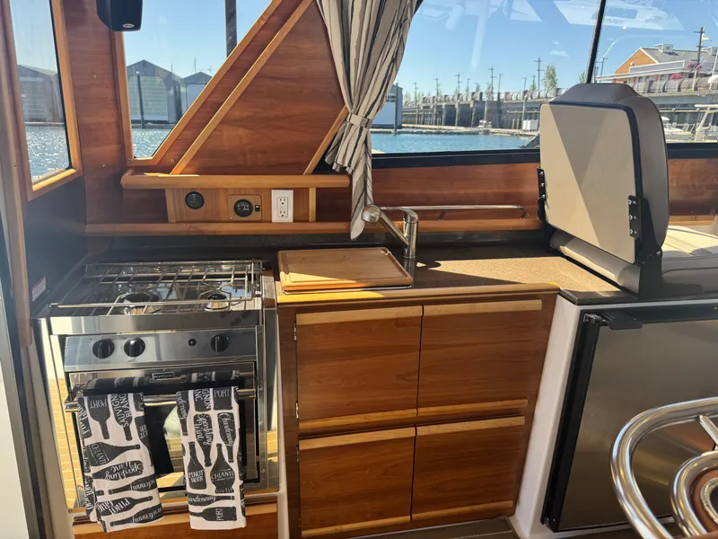 Slide: The Image of Interior of 2021 Cutwater C-28 boat kitchen with stove, sink, and wooden cabinetry. - 17