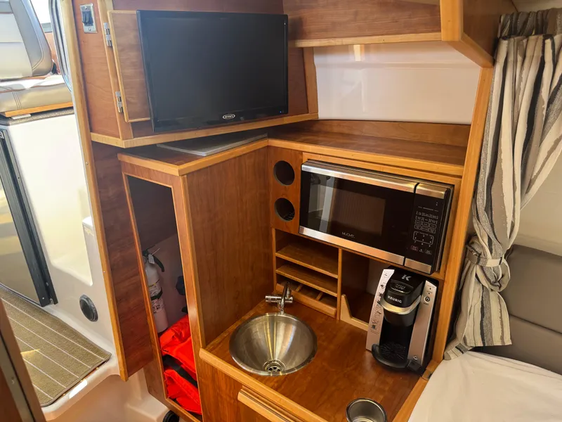 Slide: The Image of 2021 Cutwater C-28 boat interior with kitchenette, TV, microwave, sink, and coffee maker. - 30