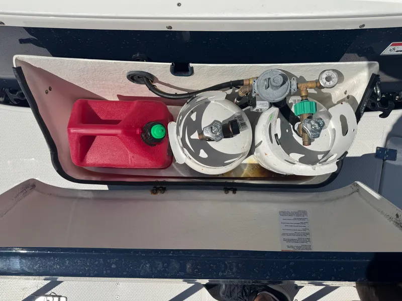 Slide: The Image of Storage compartment on a 2021 Cutwater C-28 with propane tanks and a red fuel container. - 41