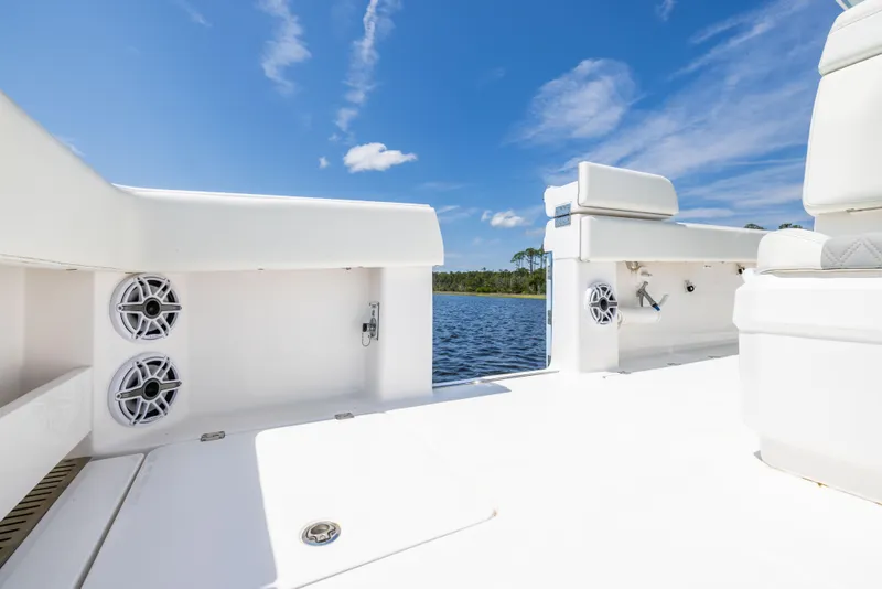 Slide: The Image of 2024 Invincible 37 Catamaran deck with speakers, white seating, and scenic water view. - 47