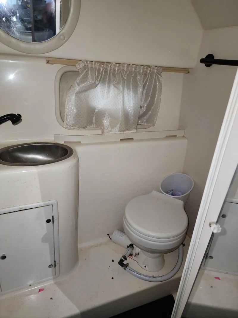 Slide: The Image of 2000 Rinker 270 Express Cruiser bathroom with sink, toilet, and window curtain. - 10